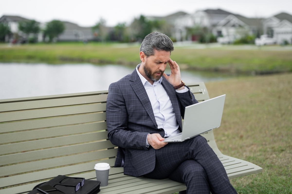 Man showing signs of low testosterone including fatigue and low energy while working outdoors on a laptop